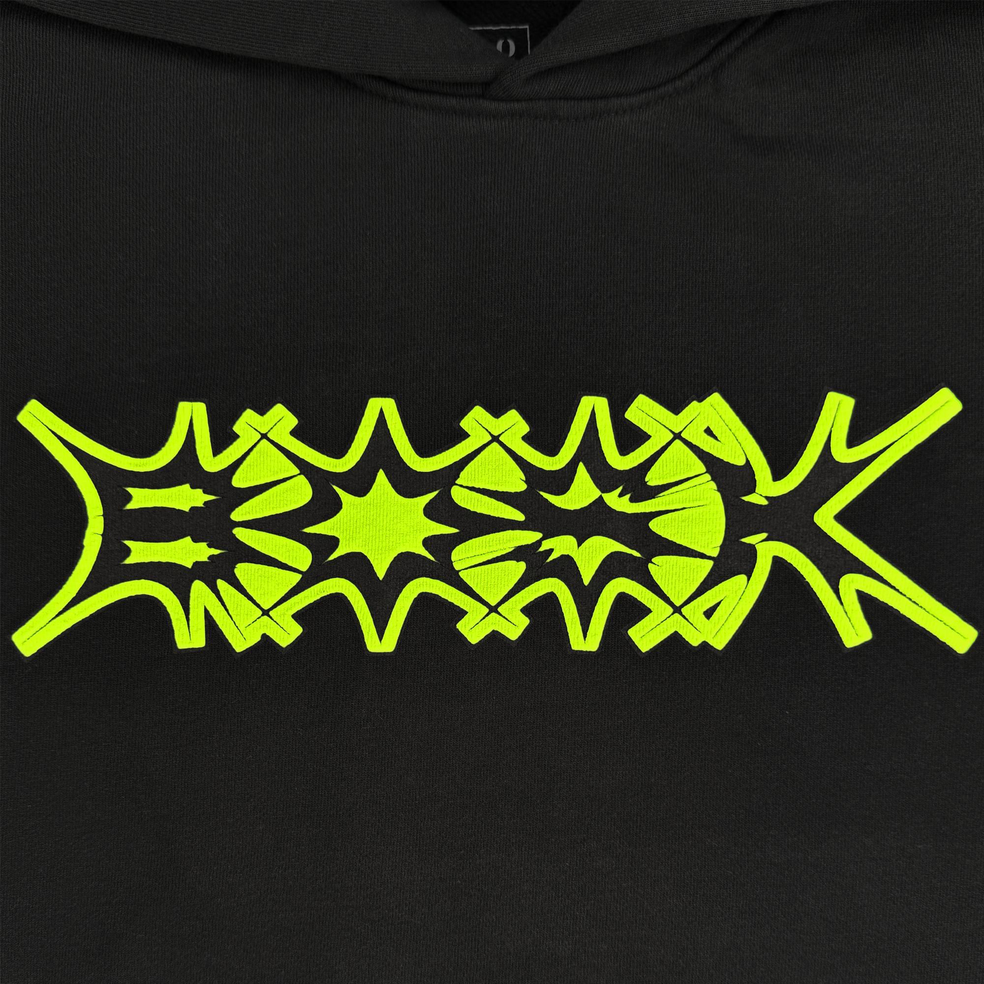The BOSK Distortion Hoodie features an abstract yellow-green design on black cotton fleece with symmetrical star-like, arrow, and geometric patterns. The pigment dye enhances depth and creates dynamic energy across the oversized drop shoulder fabric.