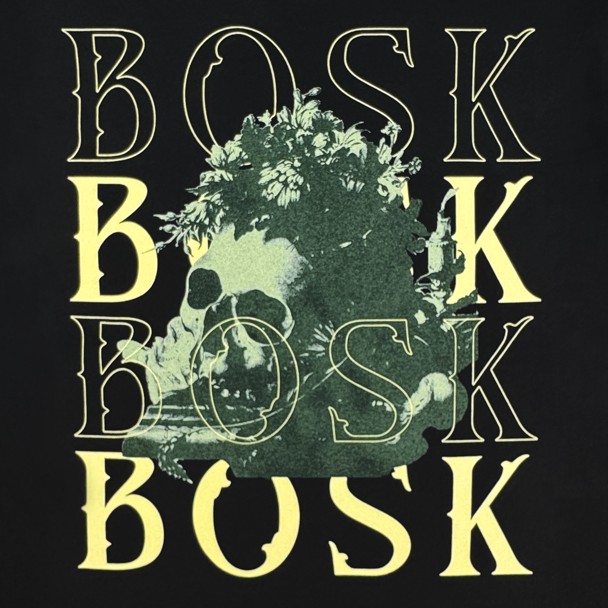 The Allure LS Tee by BOSK is a black, heavyweight cotton long sleeve featuring "BOSK" in bold yellow four times and a green skull with foliage at the center, blending nature and mortality on a solid black background.
