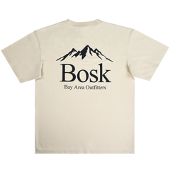 The Bosk Outdoors Tee by BOSK features a beige color with a centered mountain silhouette and the word "Bosk" in bold black text on the back. Below, smaller text reads "Bay Area Outfitters," creating a clean, outdoor-inspired aesthetic.