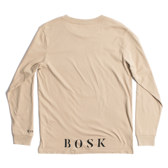 The "Rising Sun LS Tee" by BOSK is a beige long-sleeve t-shirt with a minimalistic design, featuring "BOSK" boldly printed in black on the lower back and "BO" on the sleeve. Made from 100% cotton, this classic fit shirt is displayed laid flat to highlight its back view.
